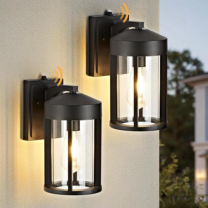 Two black outdoor wall lights on a light-colored wall with a blurred background.