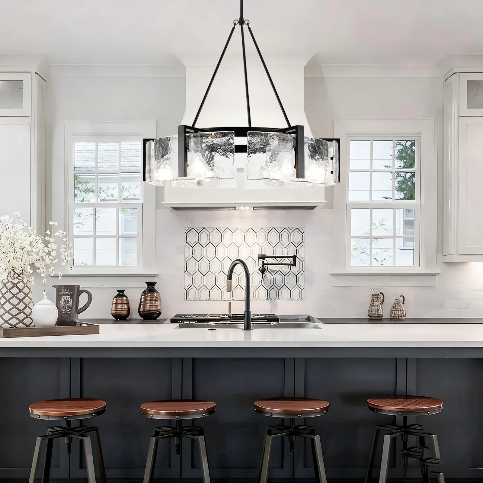 Modern kitchen with white countertops, black island, and decorative lighting fixture.