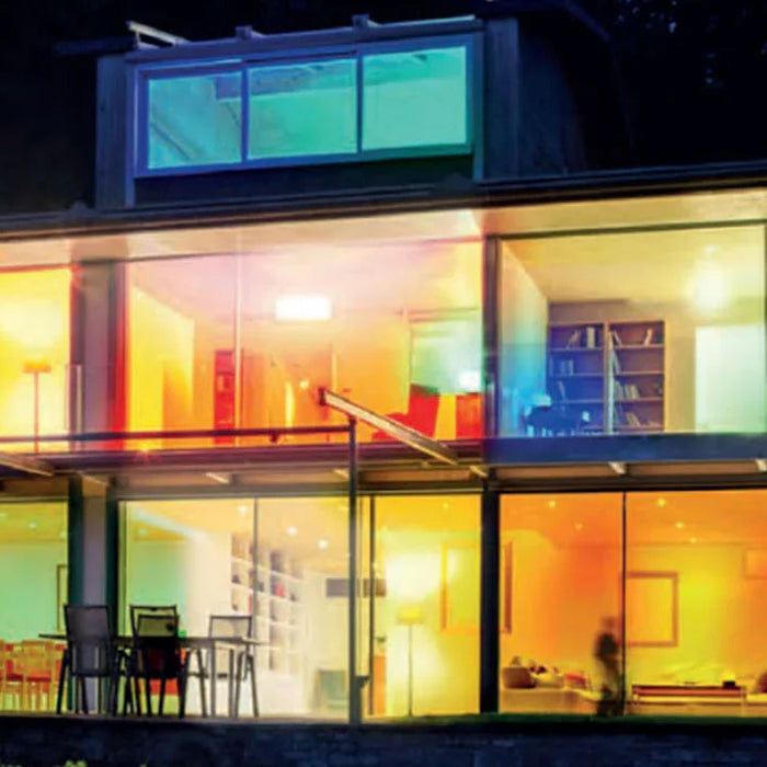 Modern house with large glass windows displaying colorful dimmable LED lights at night