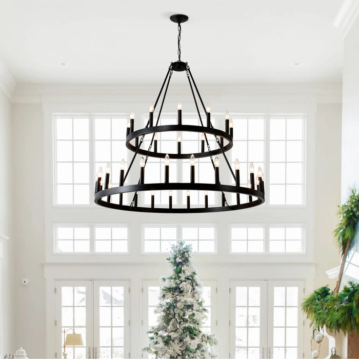 Two-tier black wagon wheel chandelier in bright farmhouse living room with large windows and Christmas tree.