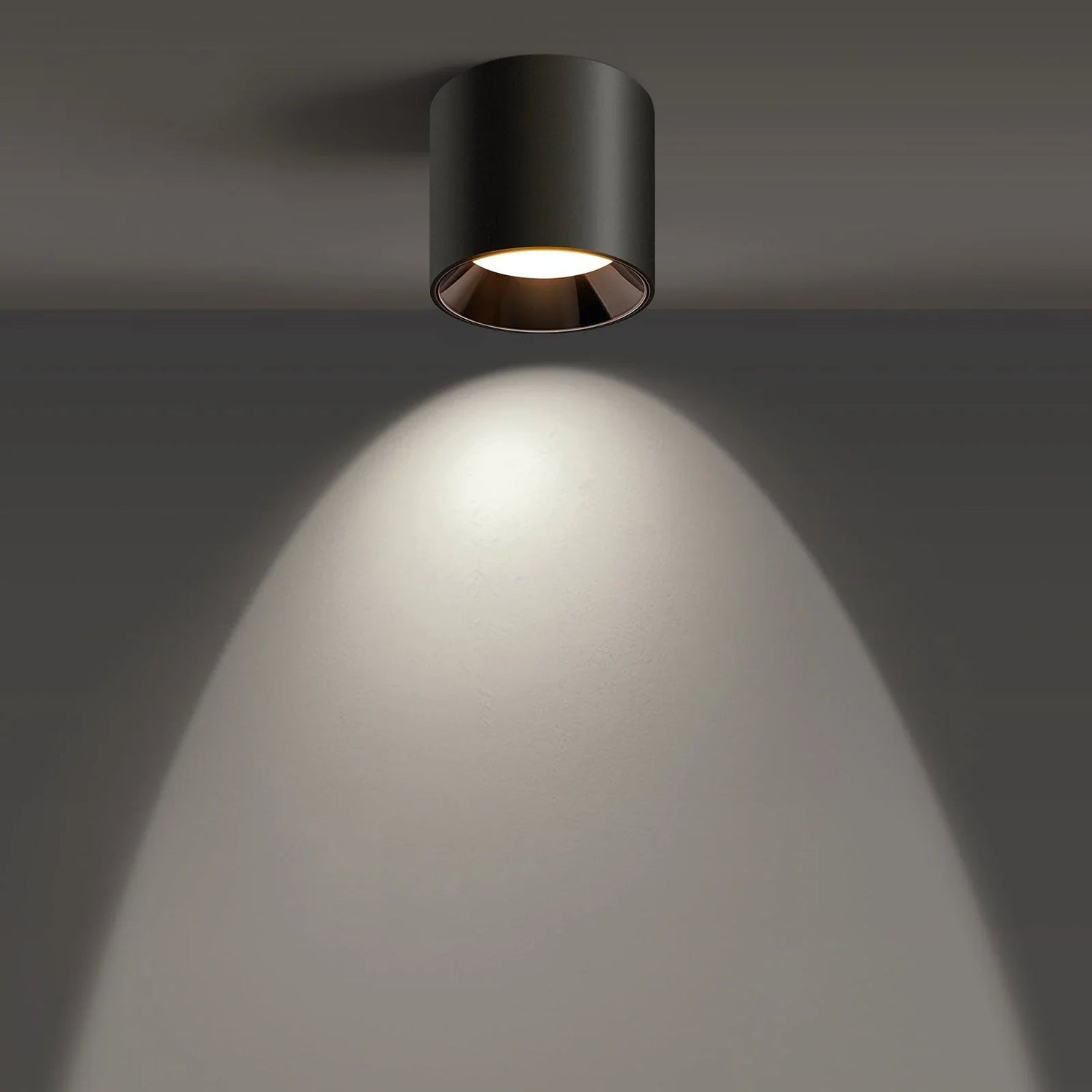Modern black ceiling light fixture illuminating a wall in a minimalist interior