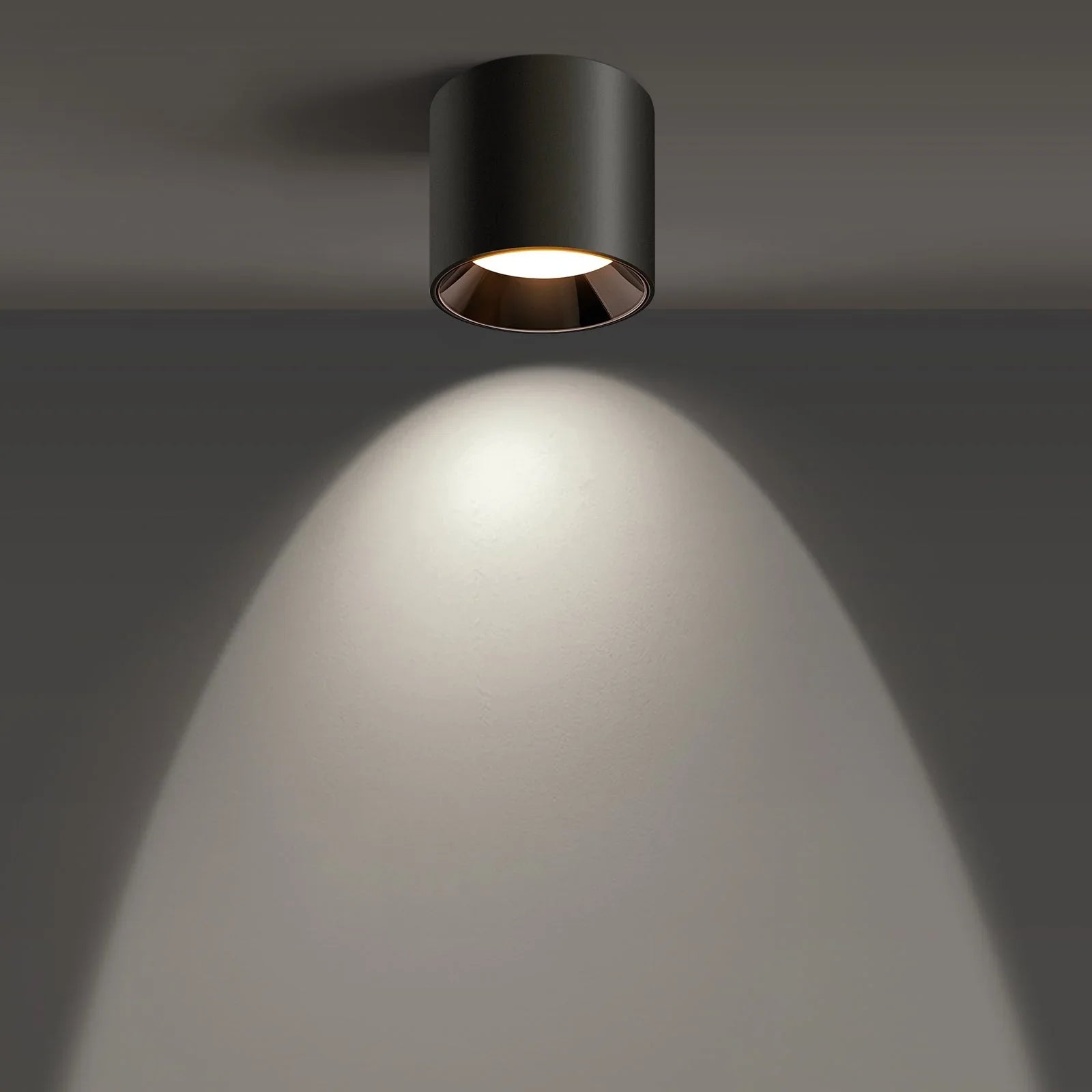 Modern black ceiling light fixture illuminating a wall in a minimalist interior