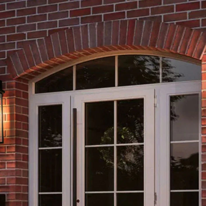 Classic black outdoor wall lights on red brick house next to white double doors