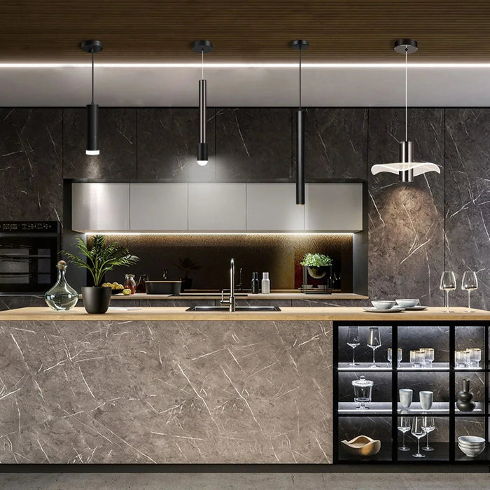 Modern kitchen with marble island, pendant lighting, glassware, and large potted plants