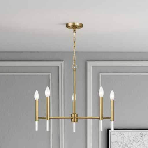 Gold chandelier hanging in a room with gray walls and a framed picture.