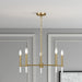 Gold chandelier hanging in a room with gray walls and a framed picture.