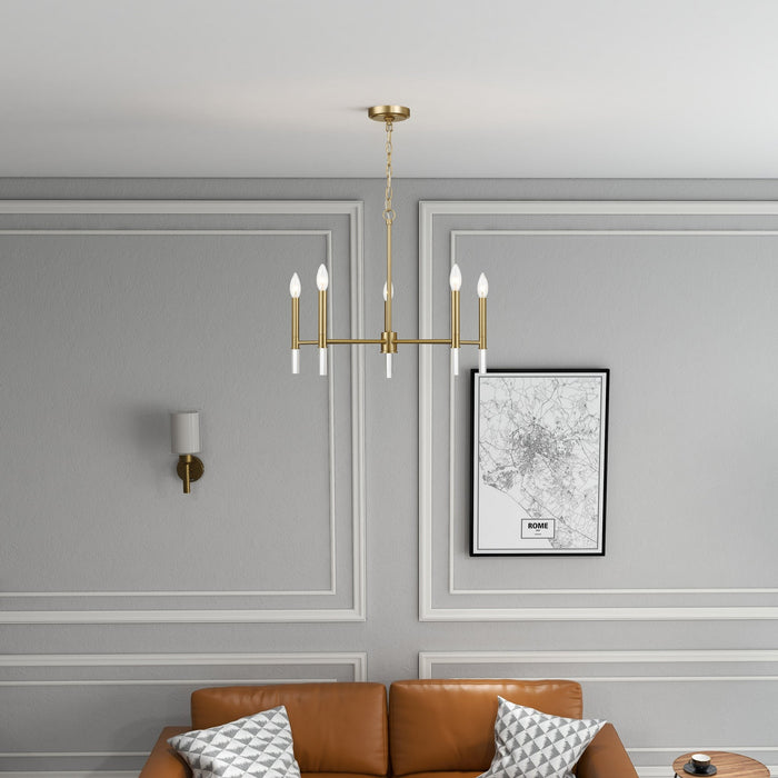 Gold chandelier hanging above a brown sofa in a living room with gray walls and a framed picture.