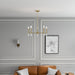 Gold chandelier hanging above a brown sofa in a living room with gray walls and a framed picture.